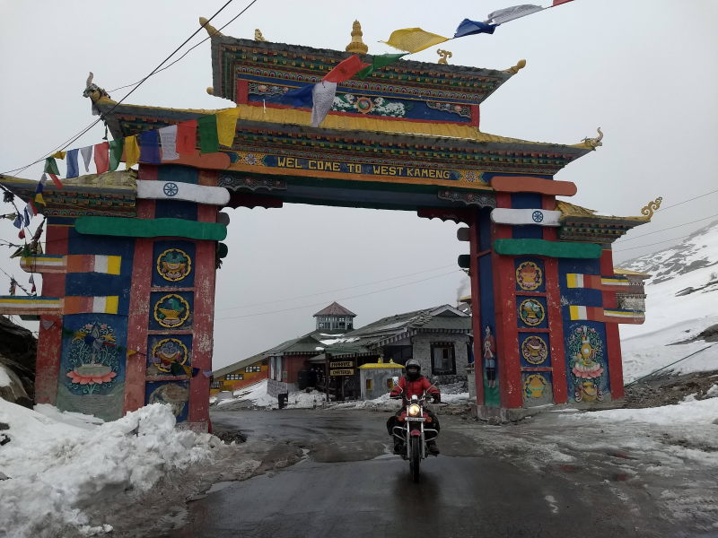 Hari rides his motorbike under the Sela pass gateway to cross over to Tawang district.